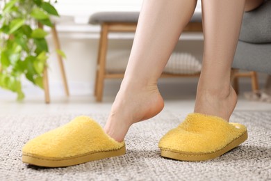 Woman wearing yellow soft slippers at home, closeup