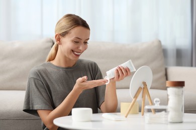 Young woman applying cream onto hand at home. Spa treatments