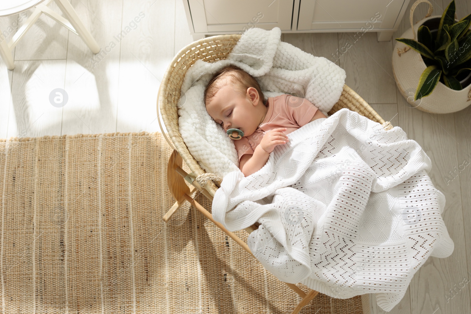 Photo of Cute little baby with pacifier sleeping in wicker crib at home, top view. Space for text