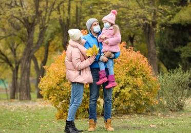 Photo of Family in medical masks outdoors on autumn day. Protective measures during coronavirus quarantine