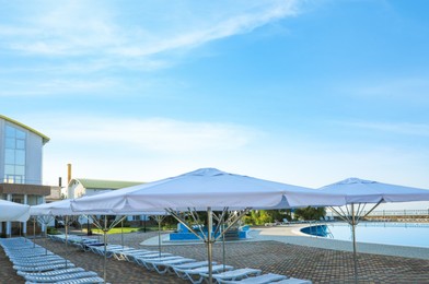 Photo of Beach umbrellas and sunbeds near outdoor swimming pool at resort