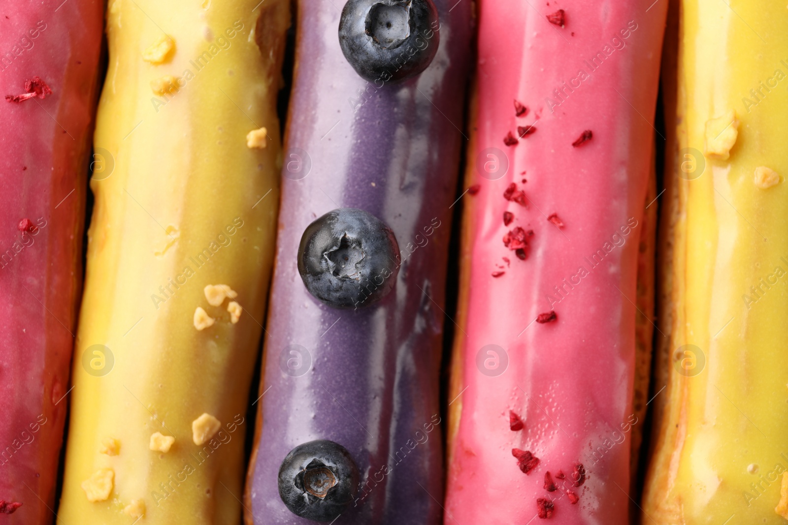 Photo of Different tasty glazed eclairs as background, above view