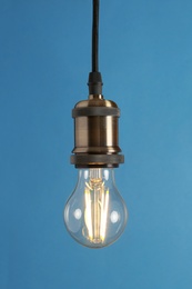 Photo of Hanging modern lamp bulb against blue background