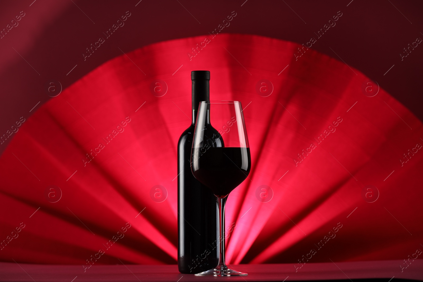 Photo of Stylish presentation of delicious red wine in bottle and glass on color background