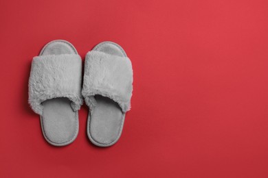 Photo of Pair of soft fluffy slippers on red background, top view. Space for text