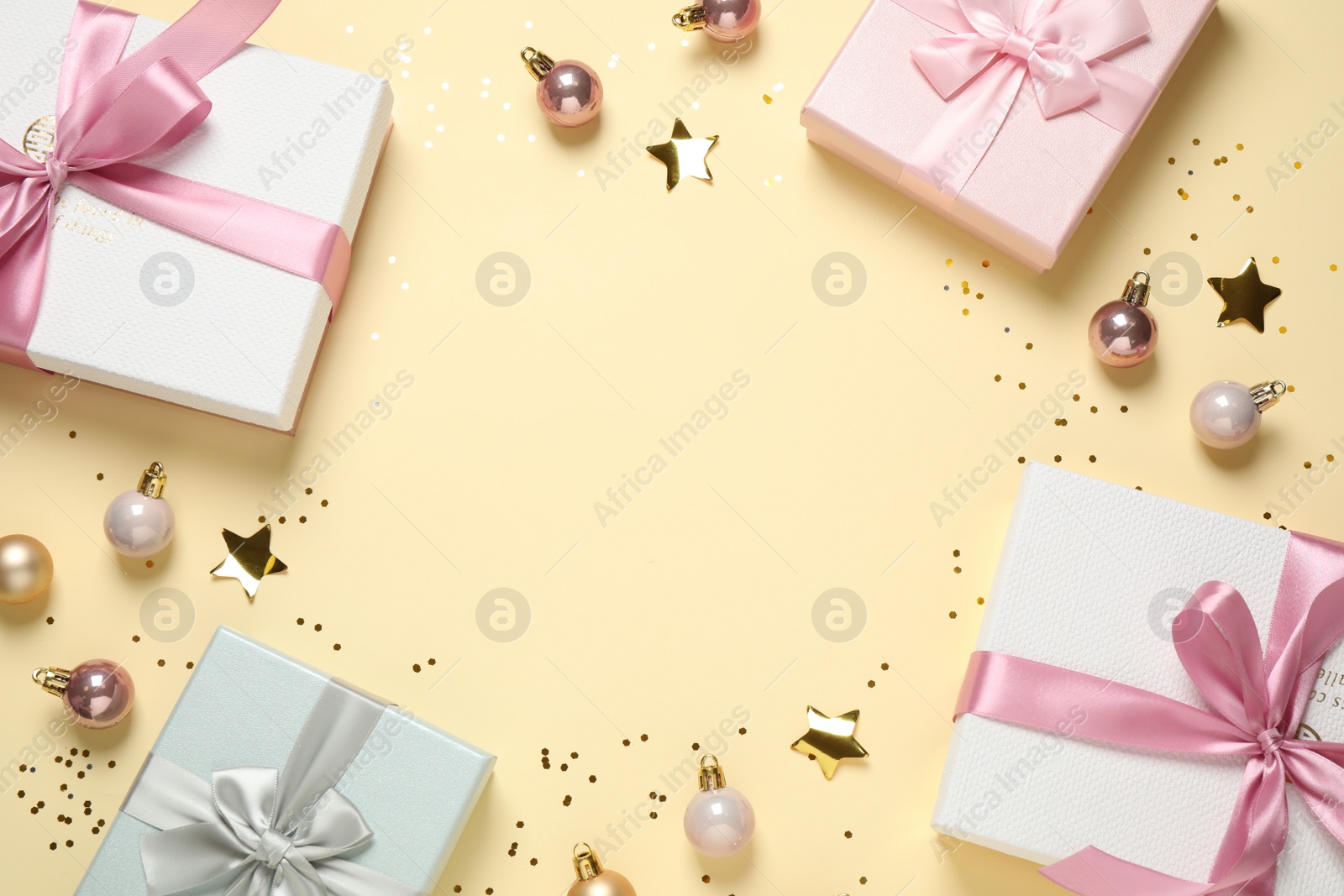 Photo of Frame of beautiful gift boxes and Christmas balls on beige background, flat lay. Space for text