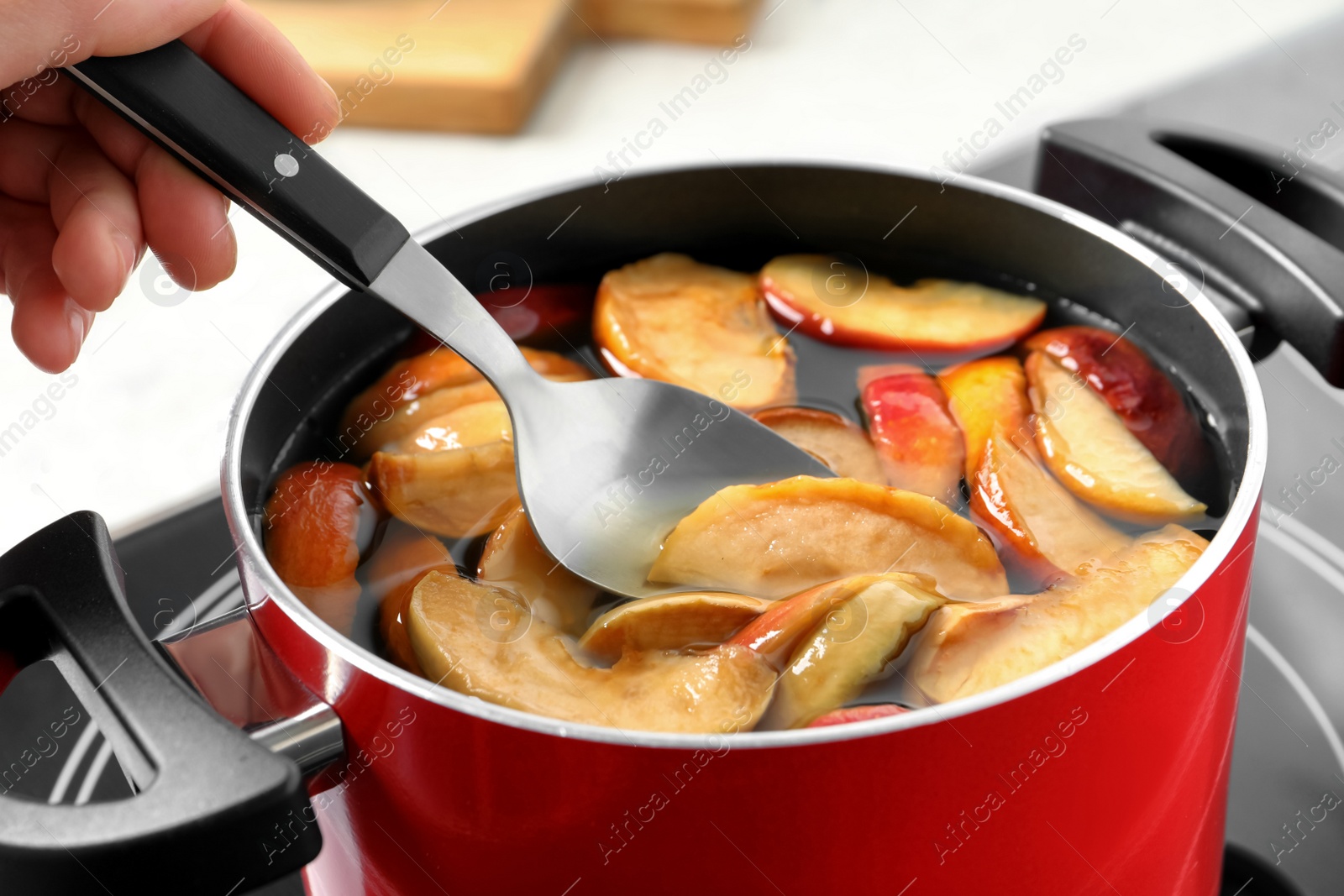 Photo of Woman making delicious compot in pot on stove, closeup