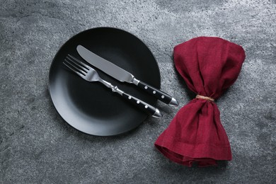 Photo of Black plate, for, knife and napkin on grey table, flat lay