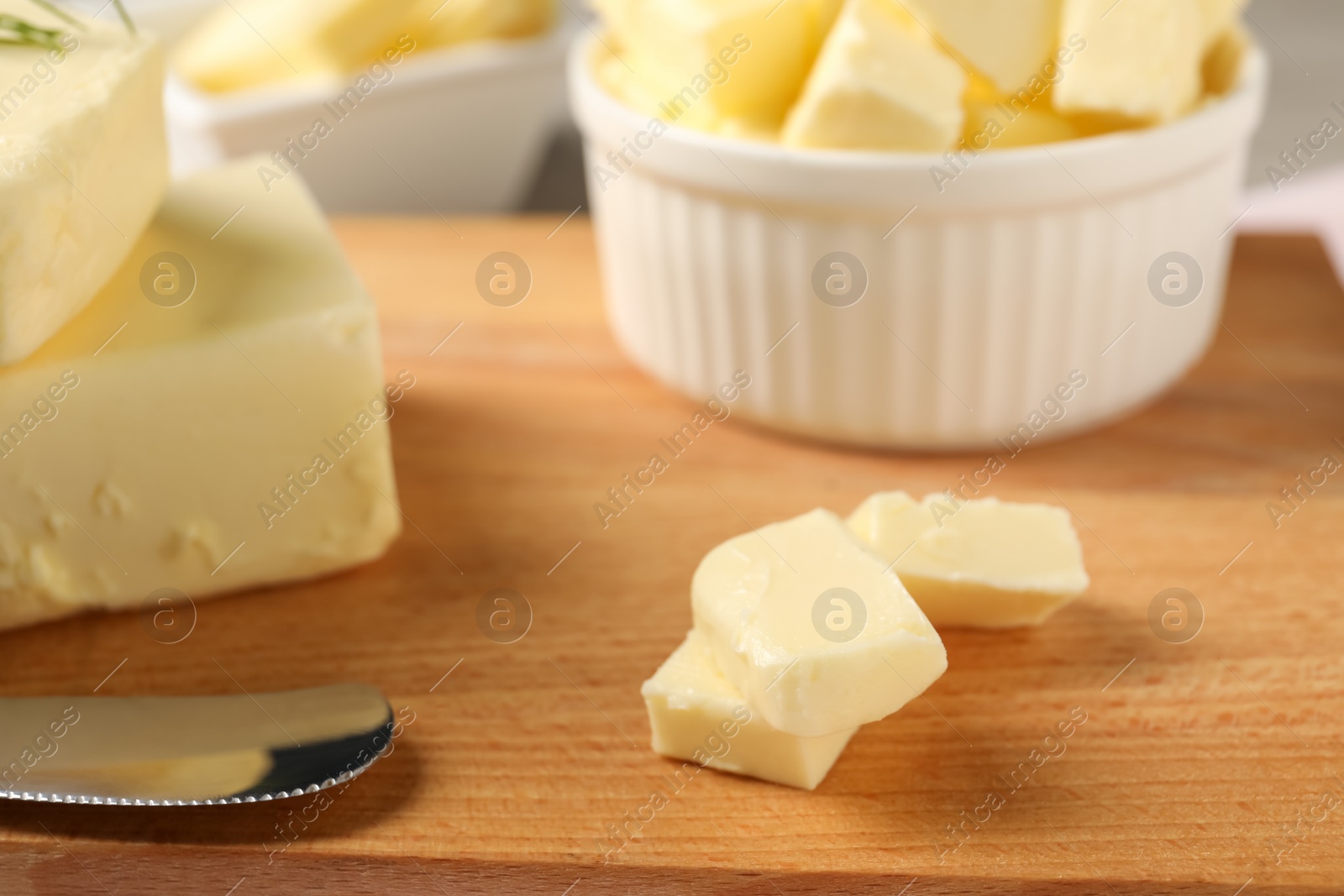 Photo of Pieces of tasty butter on wooden board, closeup