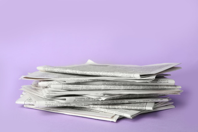 Photo of Stack of newspapers on light violet background. Journalist's work