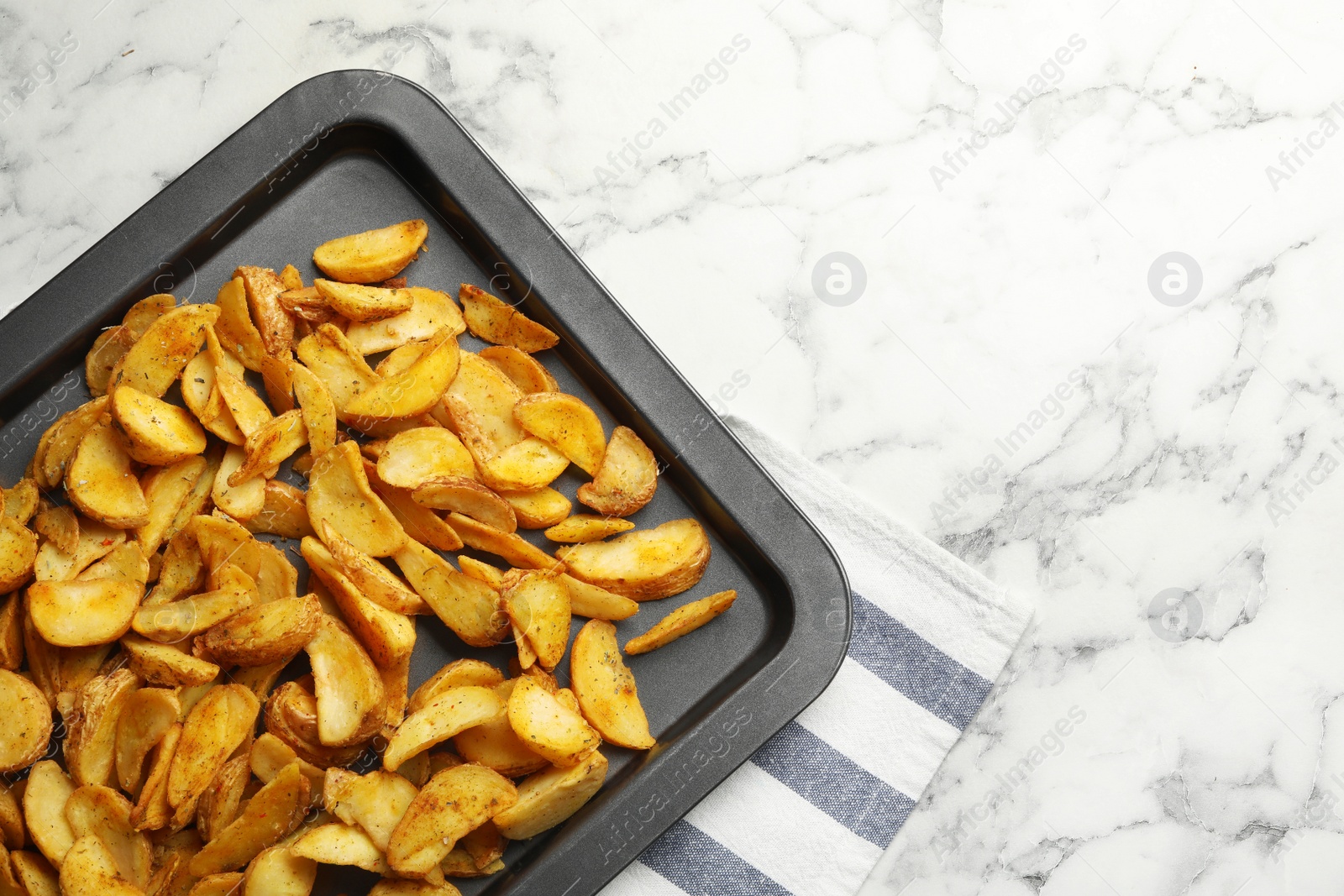 Photo of Sheet pan with delicious oven baked potatoes on marble background, flat lay. Space for text