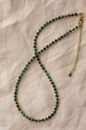 Photo of Beautiful necklace with gemstones on light cloth, top view