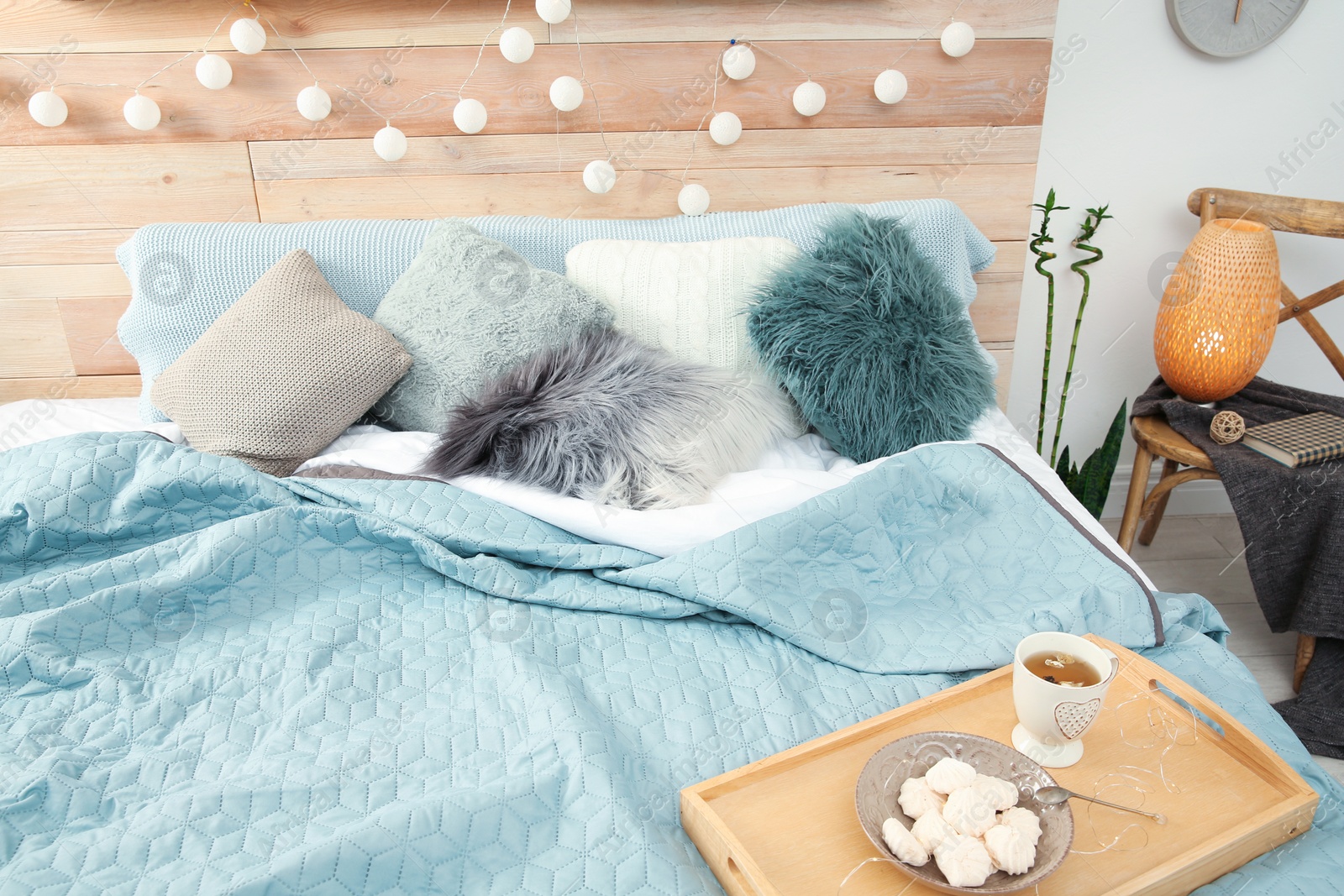 Photo of Different pillows and tray with breakfast on bed in room. Idea for interior decor