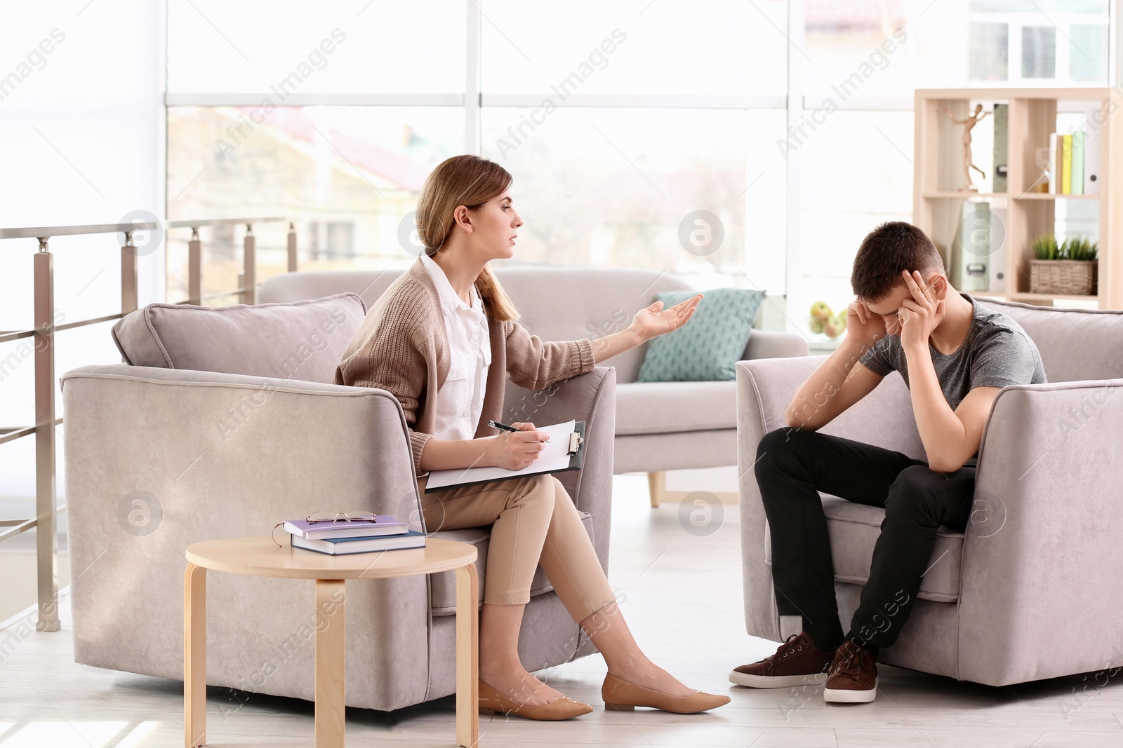 Photo of Young female psychologist working with teenage boy in office