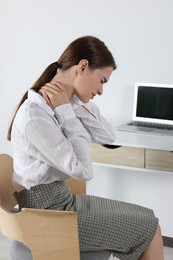 Woman suffering from neck pain in office