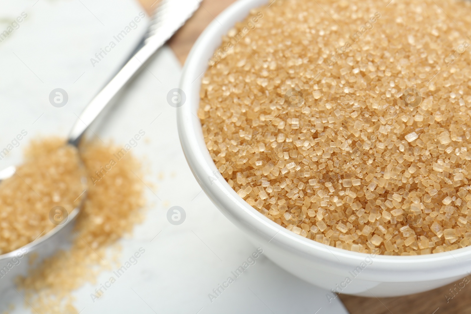 Photo of Brown sugar in bowl on white table, closeup