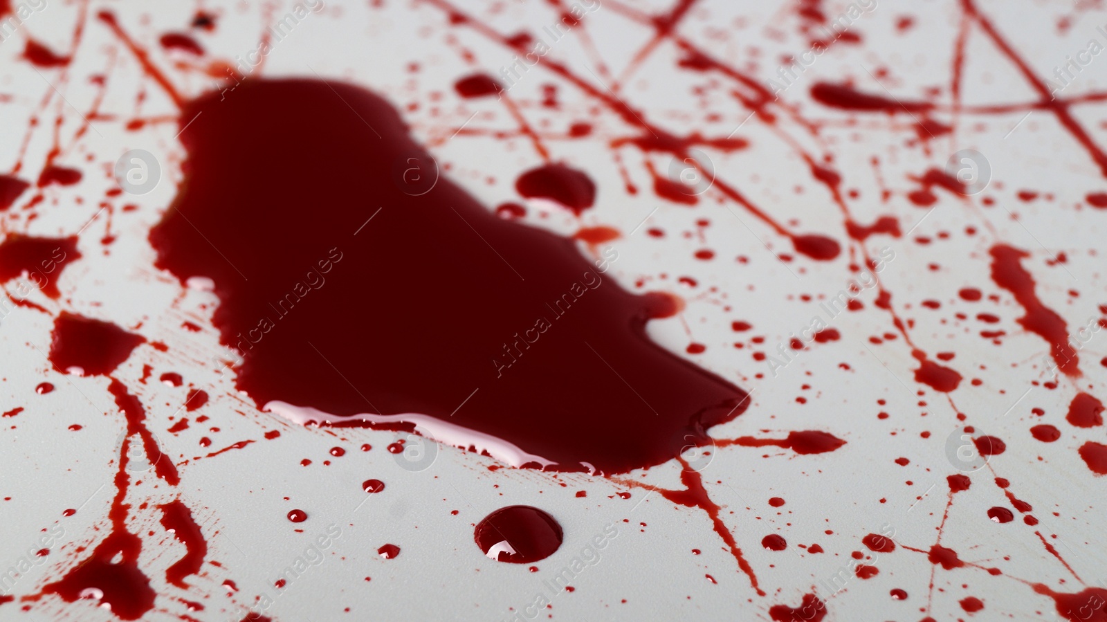 Photo of Stain and splashes of blood on light grey background, closeup