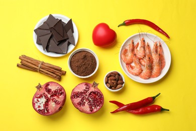Photo of Natural aphrodisiac. Different products and heart model on yellow background, flat lay