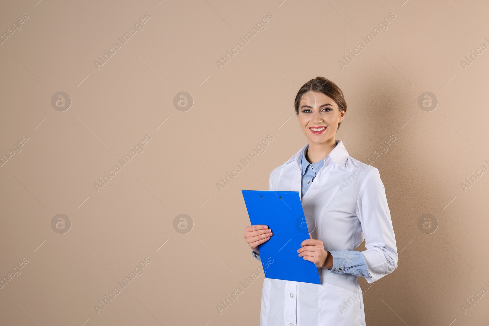 Photo of Young medical student with clipboard on color background. Space for text