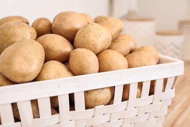 Photo of Basket with potatoes on kitchen counter, closeup. Orderly storage