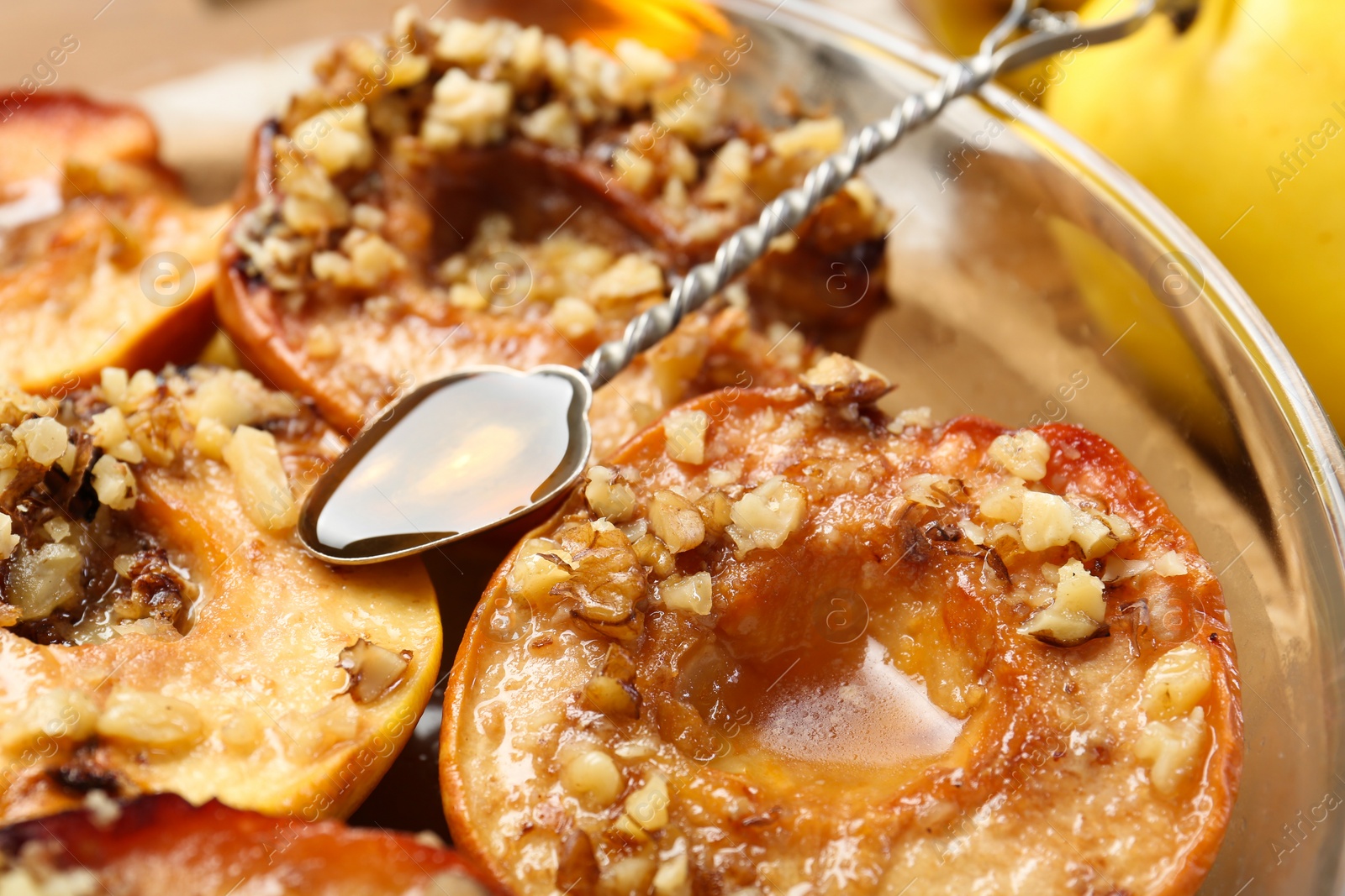 Photo of Tasty baked quinces with walnuts and honey in bowl on table, closeup