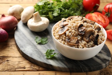 Photo of Delicious pearl barley in bowl served on wooden table