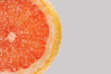 Photo of Slice of grapefruit in sparkling water on light background, closeup with space for text. Citrus soda