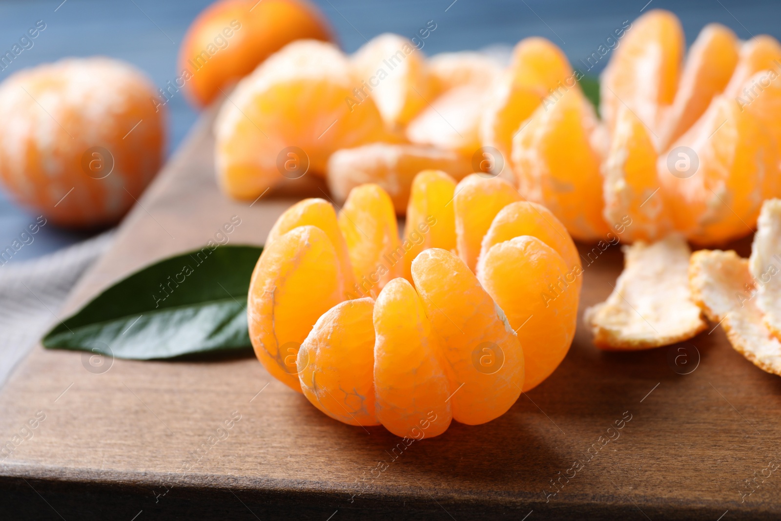 Photo of Peeled ripe tangerine on wooden board, closeup