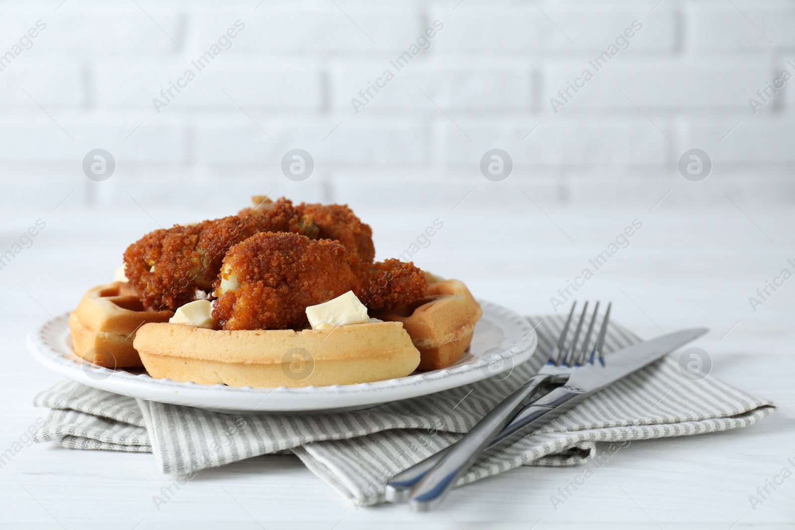 Photo of Delicious Belgium waffles served with fried chicken and butter on white table, closeup. Space for text