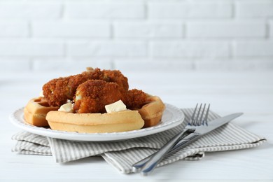 Delicious Belgium waffles served with fried chicken and butter on white table, closeup. Space for text