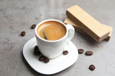 Photo of Delicious coffee and wafers for breakfast on grey table