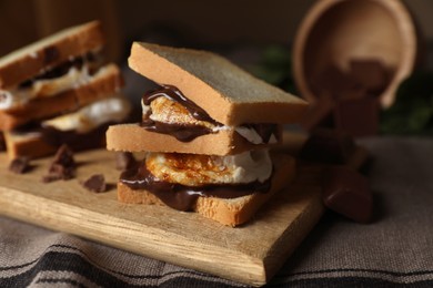Photo of Delicious marshmallow sandwiches with bread and chocolate on wooden board, closeup. Space for text