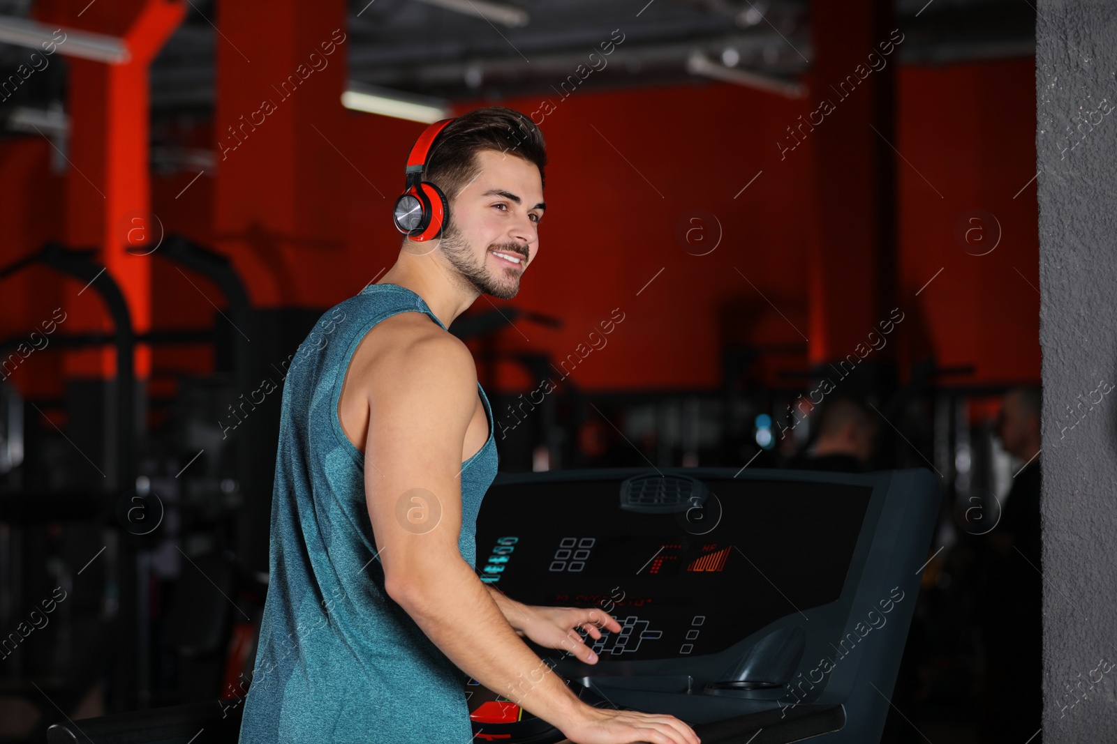 Photo of Young man listening to music with headphones at gym