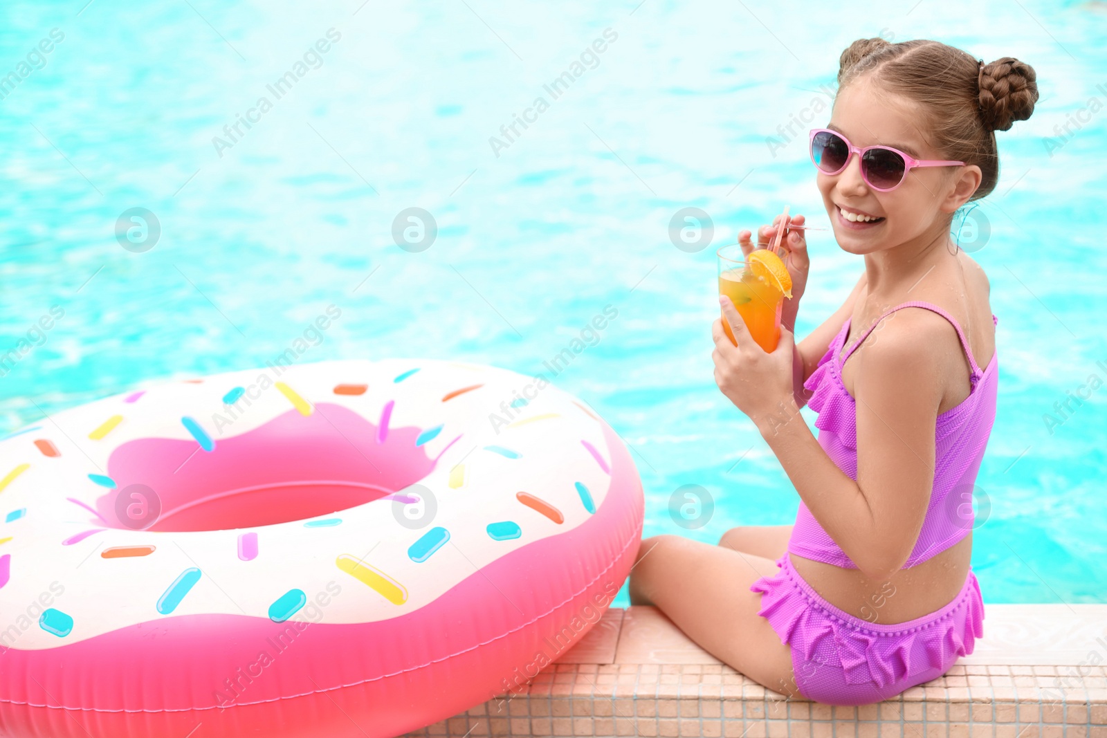 Photo of Little girl with cocktail near pool on sunny day