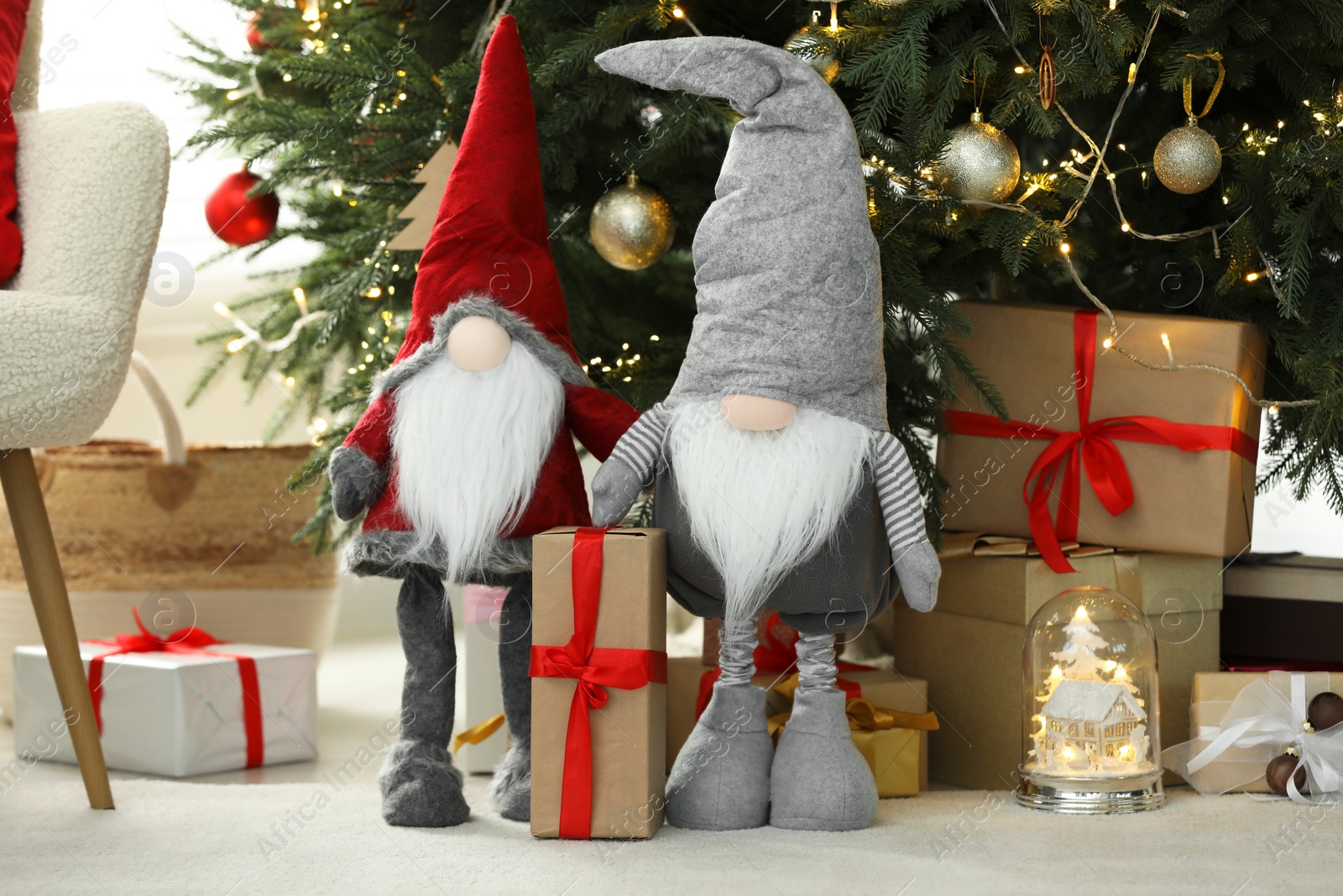 Photo of Funny decorative gnomes and gift boxes under Christmas tree indoors