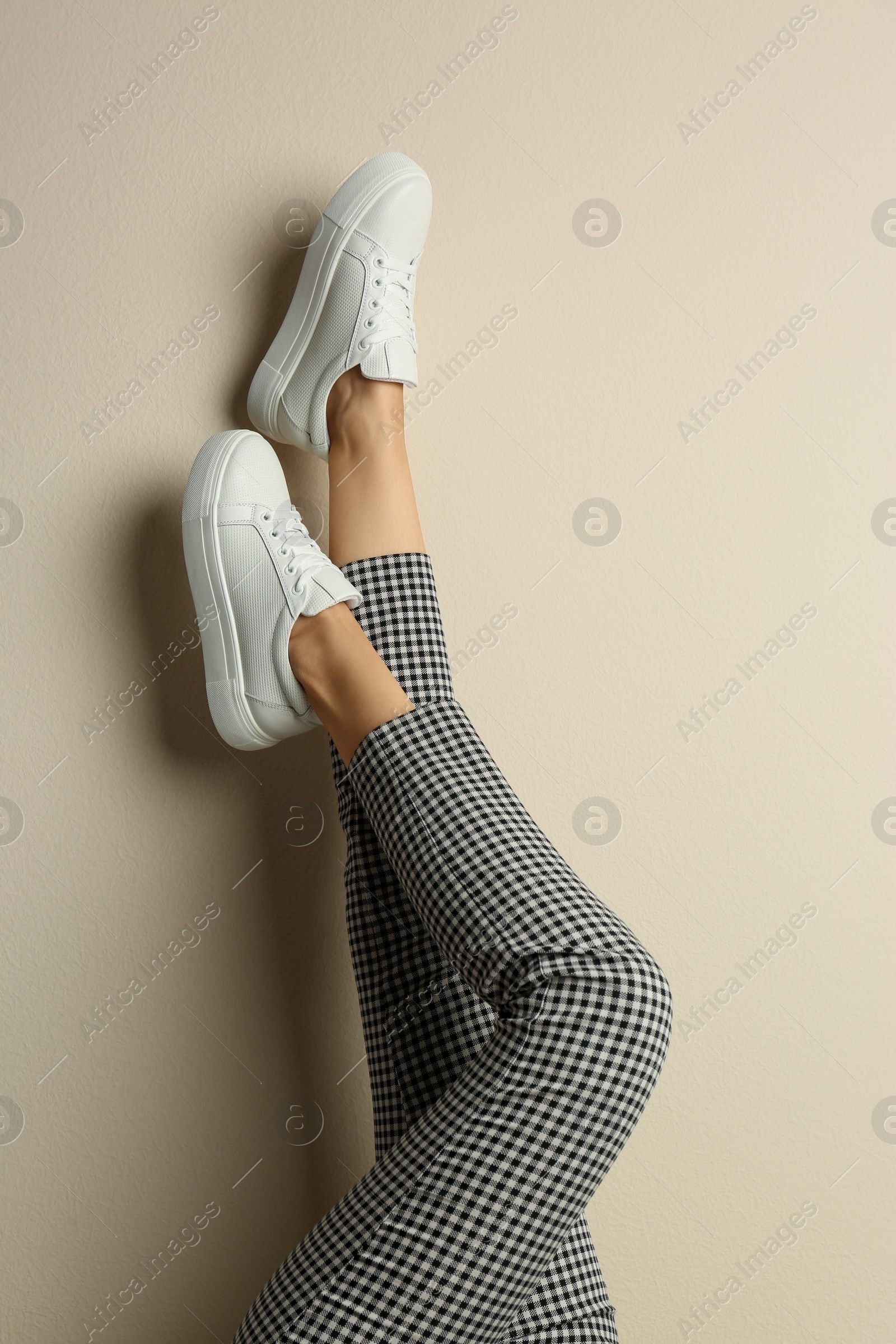 Photo of Woman wearing shoes on beige background, closeup