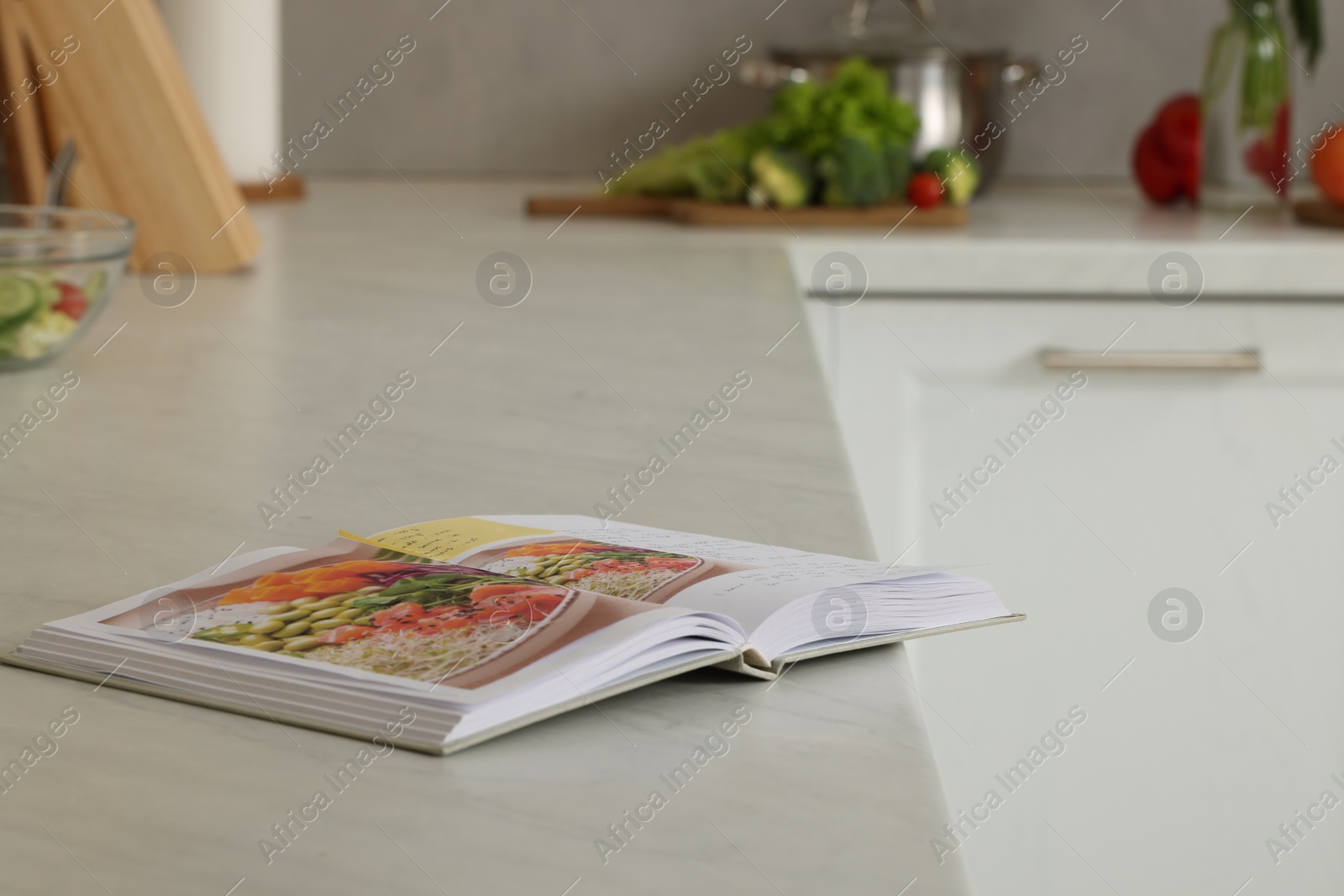 Photo of Recipe book on white marble table in kitchen, space for text