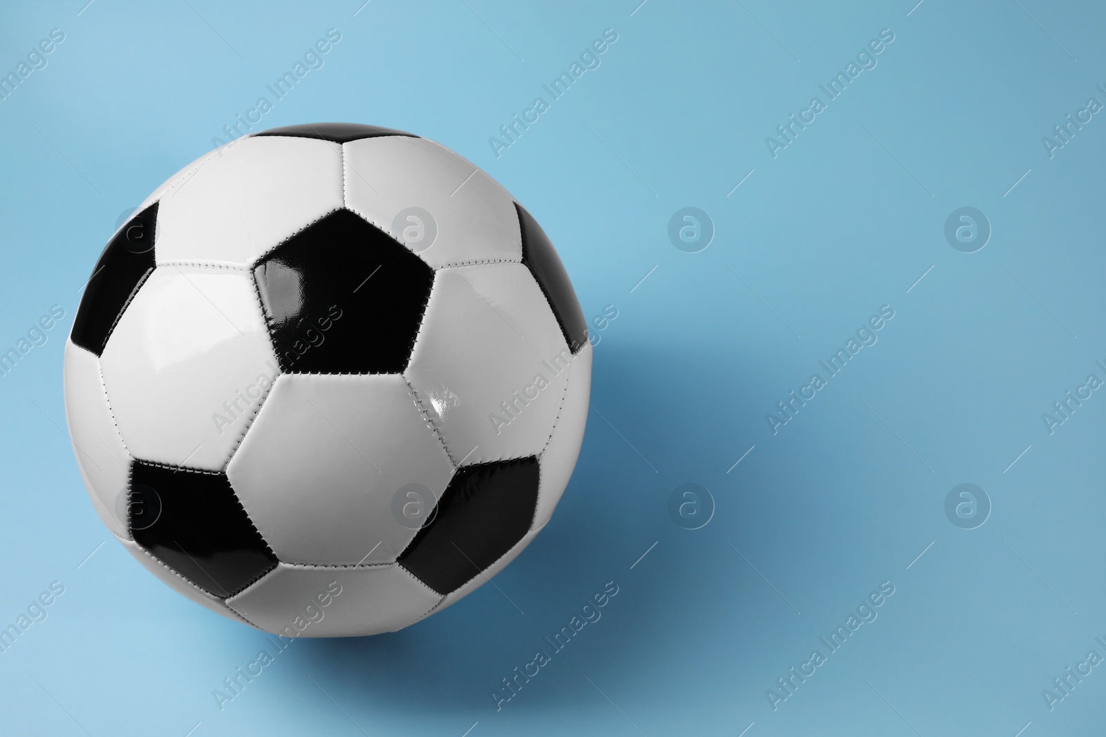 Photo of One soccer ball on light blue background, space for text. Sports equipment