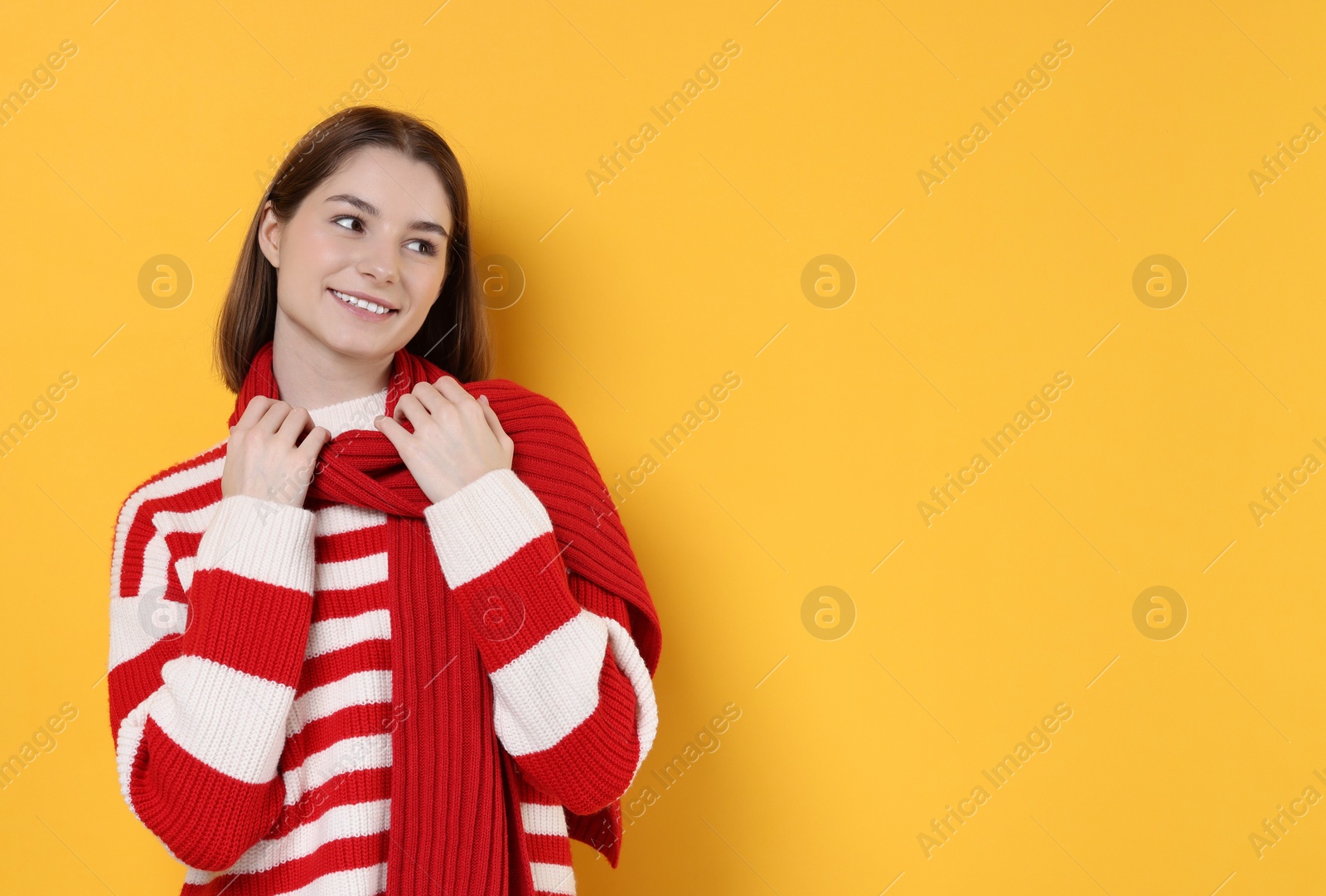 Photo of Beautiful woman in warm scarf on yellow background, space for text