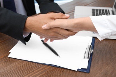 Photo of Woman shaking hands with real estate agent on meeting over table