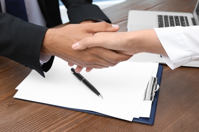 Woman shaking hands with real estate agent on meeting over table