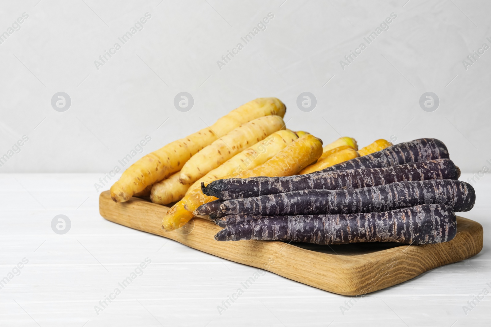 Photo of Many different raw carrots on white wooden table