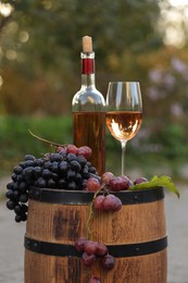 Delicious wine and ripe grapes on wooden barrel outdoors