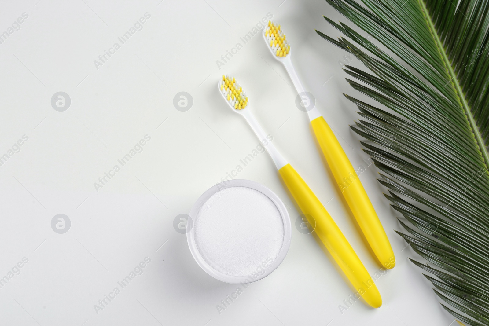 Photo of Toothbrushes and bowl of baking soda on beige background, flat lay. Space for text