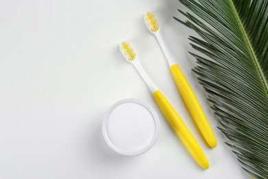 Toothbrushes and bowl of baking soda on beige background, flat lay. Space for text