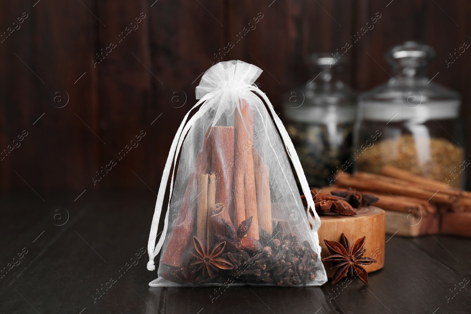 Photo of Scented sachet with cinnamon sticks and anise stars on wooden table