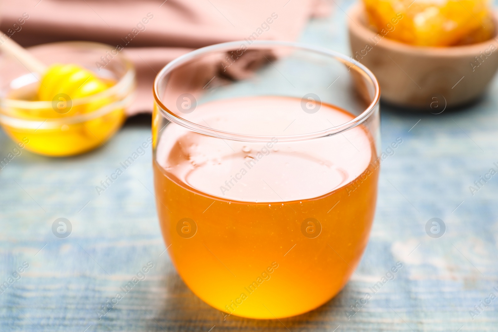 Photo of Tasty honey on light blue wooden table, closeup