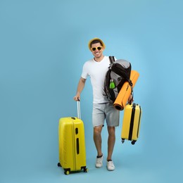 Male tourist with travel backpack and suitcases on turquoise background