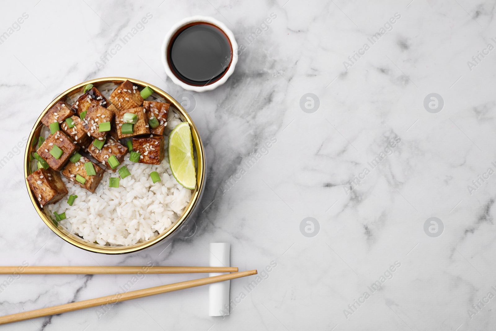 Photo of Delicious rice with fried tofu and green onions served on white marble table, flat lay. Space for text