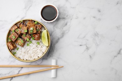 Delicious rice with fried tofu and green onions served on white marble table, flat lay. Space for text